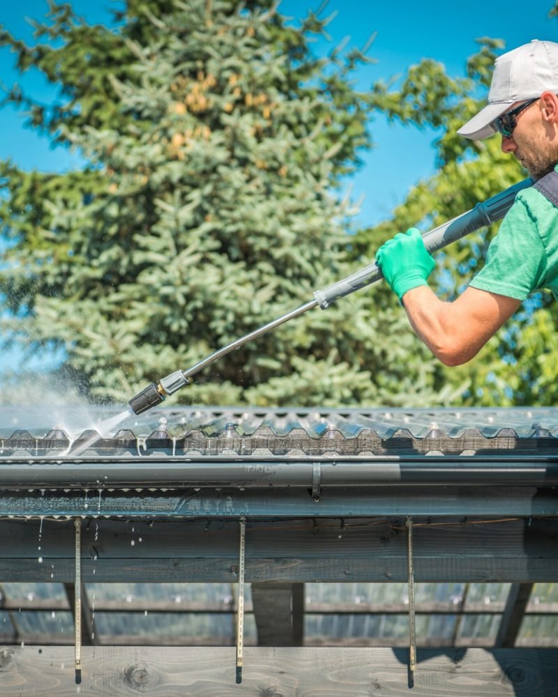 Roof and Gutters Power Cleaning Using Pressure Washer. Caucasian Worker.